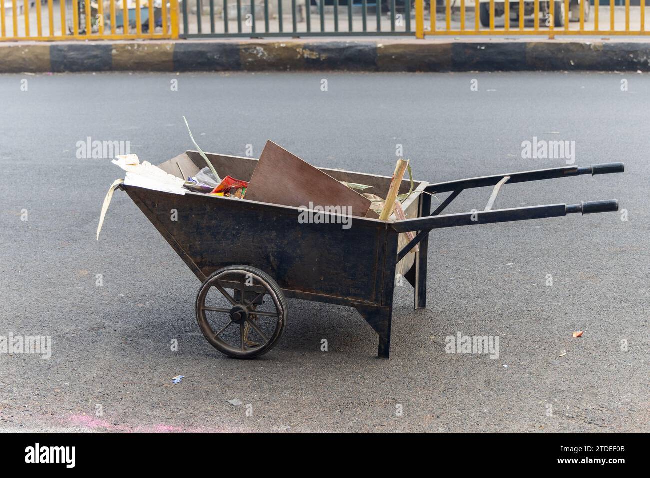 Eiserner Müllträger, gefüllt mit Garagen auf der Asphaltstraße am Morgen Stockfoto