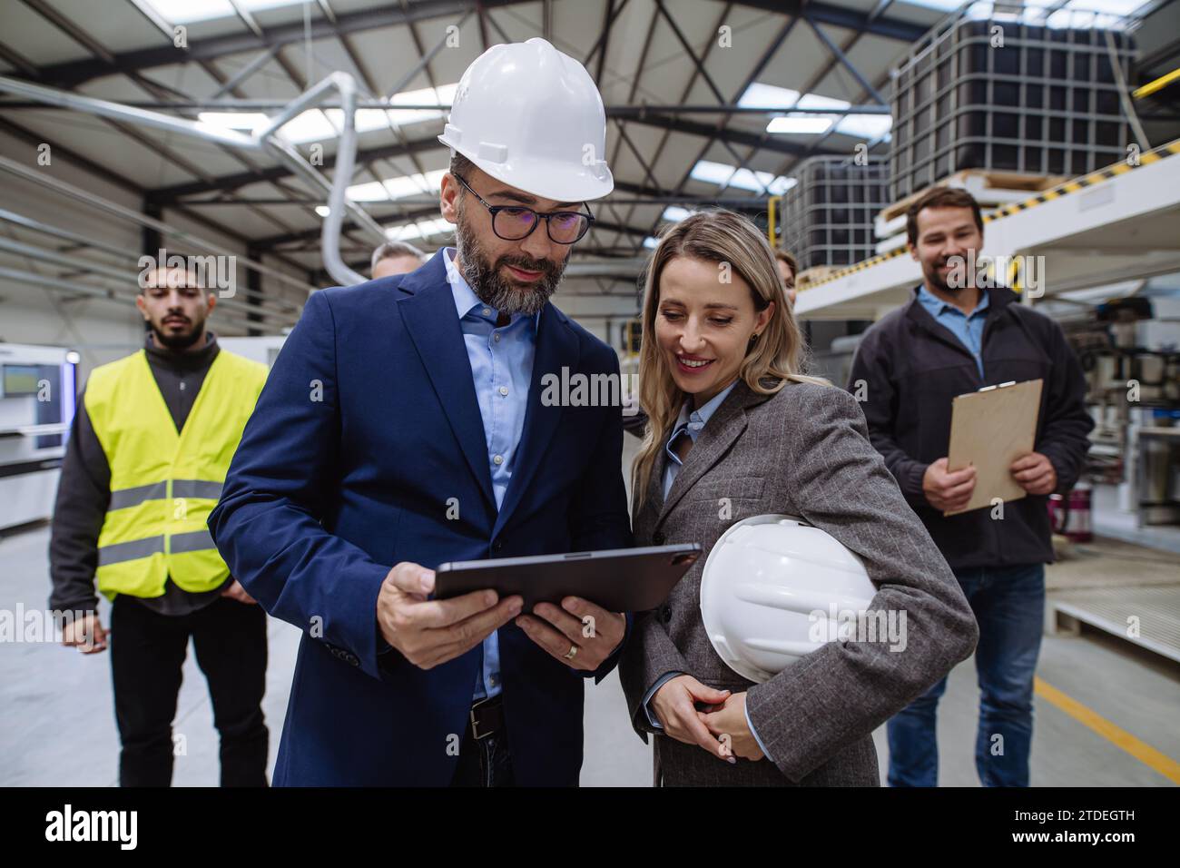 Ein komplettes Team von Lagermitarbeitern, die das Lager betreten und sich ein Tablet ansehen. Team von Arbeitern, Managern, weibliche Direktorin in modernen Industriefabriken Stockfoto