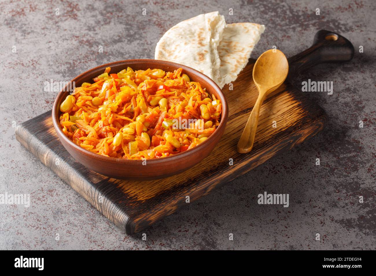 Chakalaka scharfes Gemüsegemüse mit Karotten, gebackenen Bohnen, Zwiebeln, Tomaten und Pfeffer in der Nähe auf der Schüssel auf dem Tisch. Horizontal Stockfoto