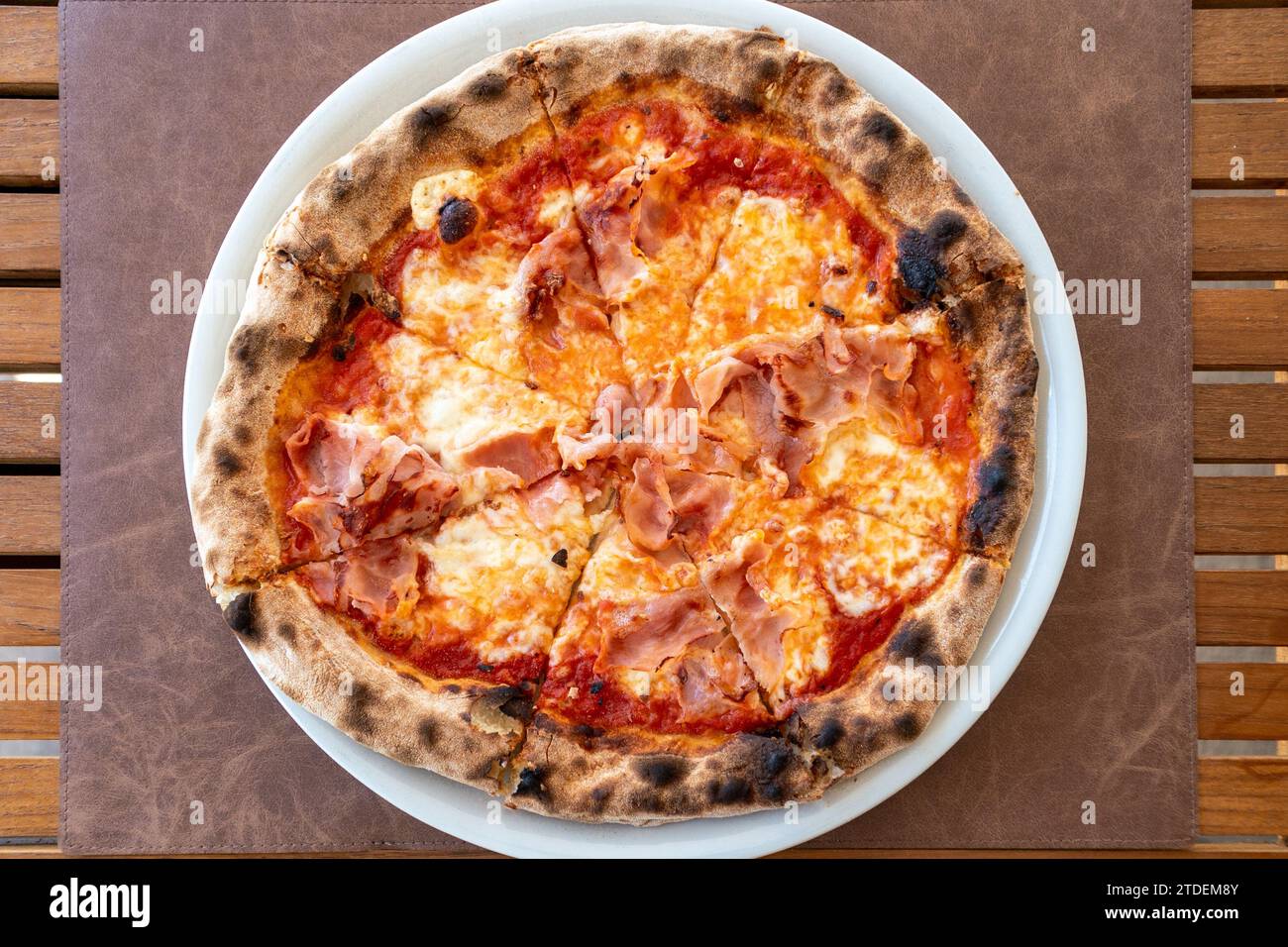 Ein Blick aus der Vogelperspektive über einen Teller mit frisch gebackenem italienischem Schinken und Käse Pizza Stockfoto