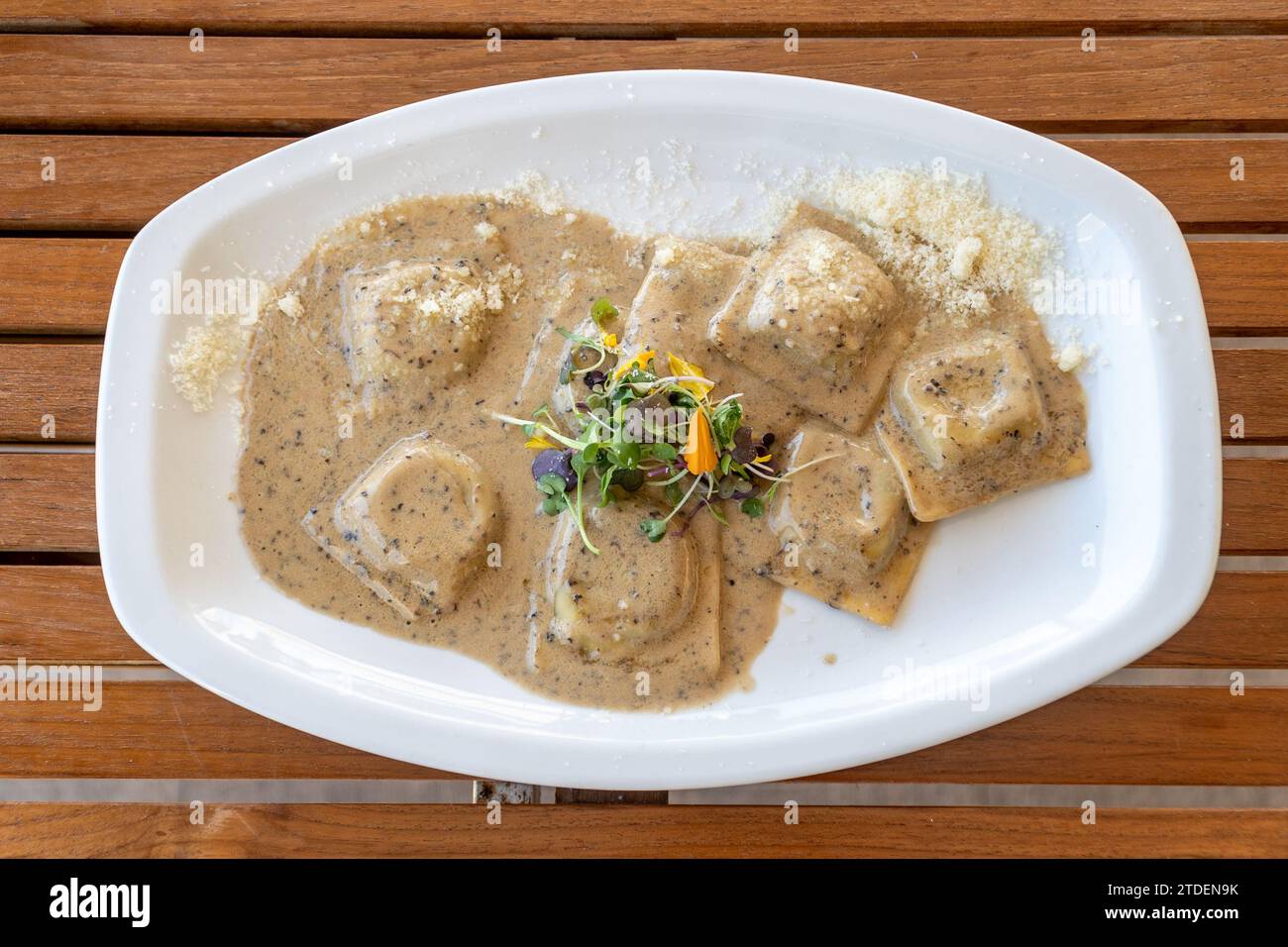 Ein Blick aus der Vogelperspektive über einen Teller mit frischen Pilzravioli italienische Pasta auf einem Holztisch Stockfoto
