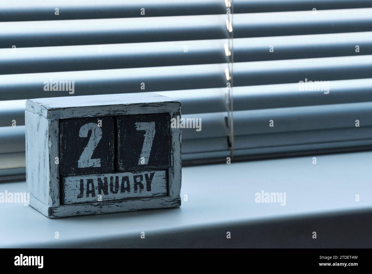 Am Morgen des 27. Januar auf Holzkalender, der auf einem Fenster mit Jalousien steht Stockfoto