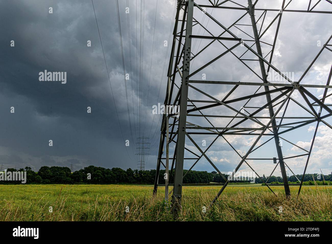 Strommasten und Stromleitungen mit dramatischen Gewitterwolken im Hintergrund Stockfoto