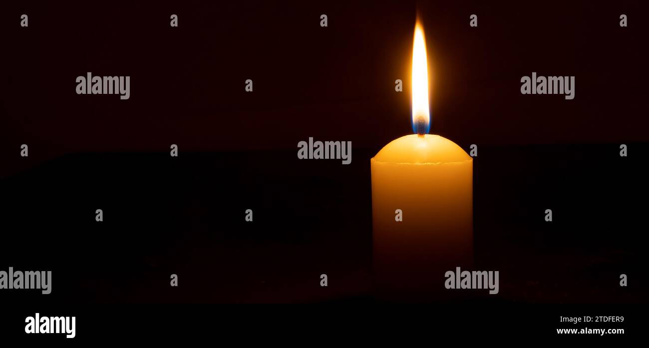 Einzelne brennende Kerzenflamme oder Licht leuchtet auf einer großen weißen Kerze auf schwarzem oder dunklem Hintergrund auf dem Tisch in der Kirche zu Weihnachten, Beerdigung Stockfoto