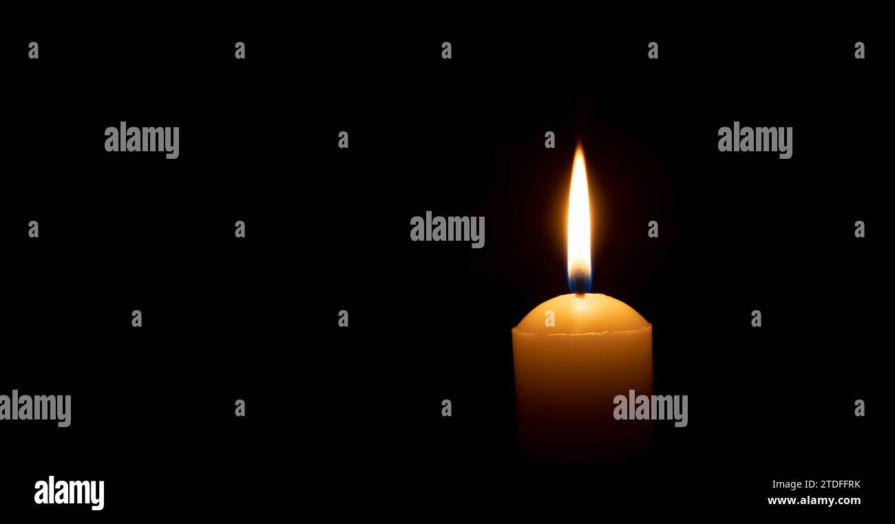 Einzelne brennende Kerzenflamme oder Licht leuchtet auf einer großen gelben Kerze auf schwarzem oder dunklem Hintergrund auf dem Tisch in der Kirche zu Weihnachten, Beerdigung Stockfoto