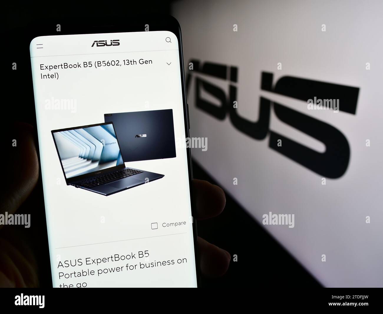 Person, die ein Mobiltelefon mit Webseite der taiwanesischen Firma ASUSTeK Computer Inc. Hält (ASUS) vor dem Logo. Konzentrieren Sie sich auf die Mitte des Telefondisplays. Stockfoto