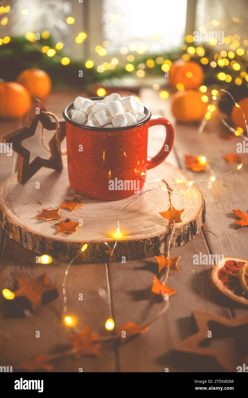 Niedliche, gemütliche Winterkomposition. Rote Tasse, Marshmallows, Orangen und Weihnachtslichter. Silvester und weihnachten, Wärme, Komfort Stockfoto