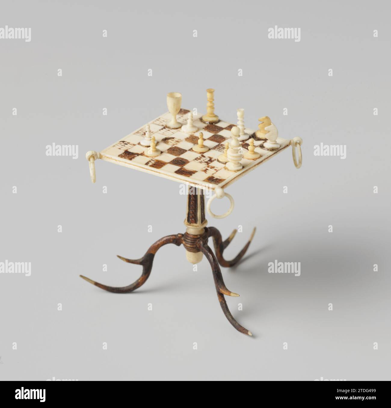 Schautisch auf einem Stamm auf drei S-förmigen Beinen, anonym, ca. 1825 - ca. 1874 Knochen-Schachtisch, das rechteckige Blatt liegt auf einem Stamm auf drei S-förmigen Beinen. Die Ringe sind an den vier Ecken der Platine angebracht. Auf dem Teller sind Schachfiguren. Deutschland Knochen (Material) Knochen Schachtisch, das rechteckige Blatt liegt auf einem Stamm auf drei S-förmigen Beinen. Die Ringe sind an den vier Ecken der Platine angebracht. Auf dem Teller sind Schachfiguren. Deutschland Knochen (Material) Stockfoto