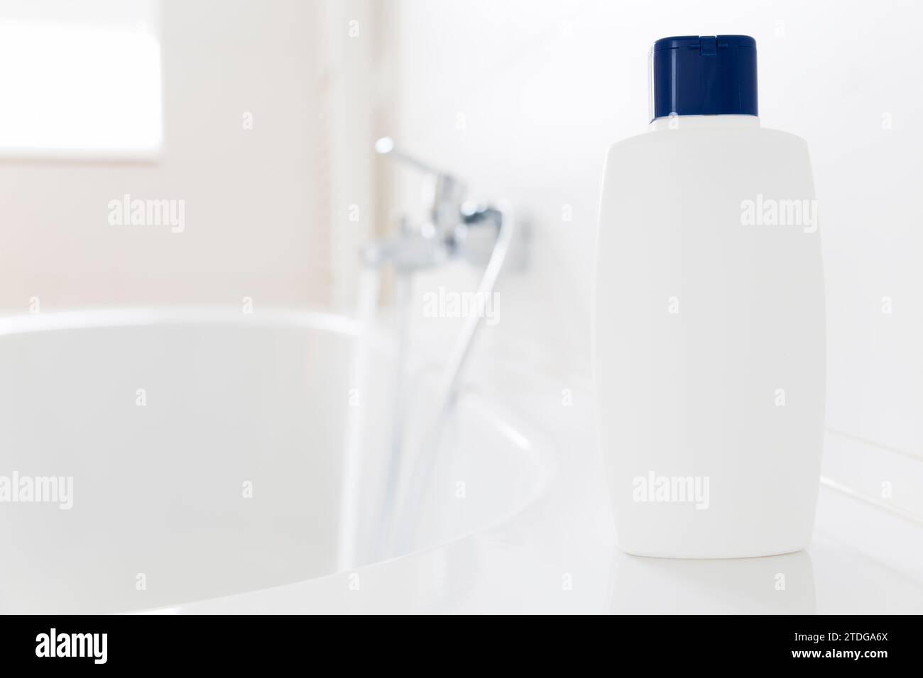 Weiße Flasche Shampoo steht auf einer Badewanne in einem hellen Badezimmer - Kopierraum auf der Flasche Stockfoto