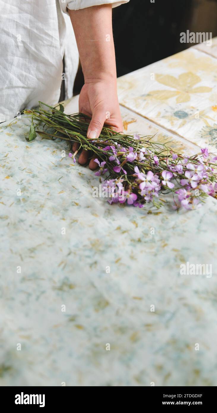 Textilkünstler, Blumenstrauß in der Hand. Stoff gefärbt mit natürlichen Blumenmustern. Botanisches Muster. Kopierbereich. Stockfoto