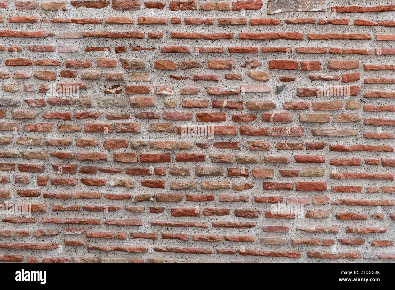 Nahaufnahme eines Abschnitts einer Ziegelmauer mit abgenutzten und verwitterten Ziegeln in verschiedenen Größen und Farben. Stockfoto