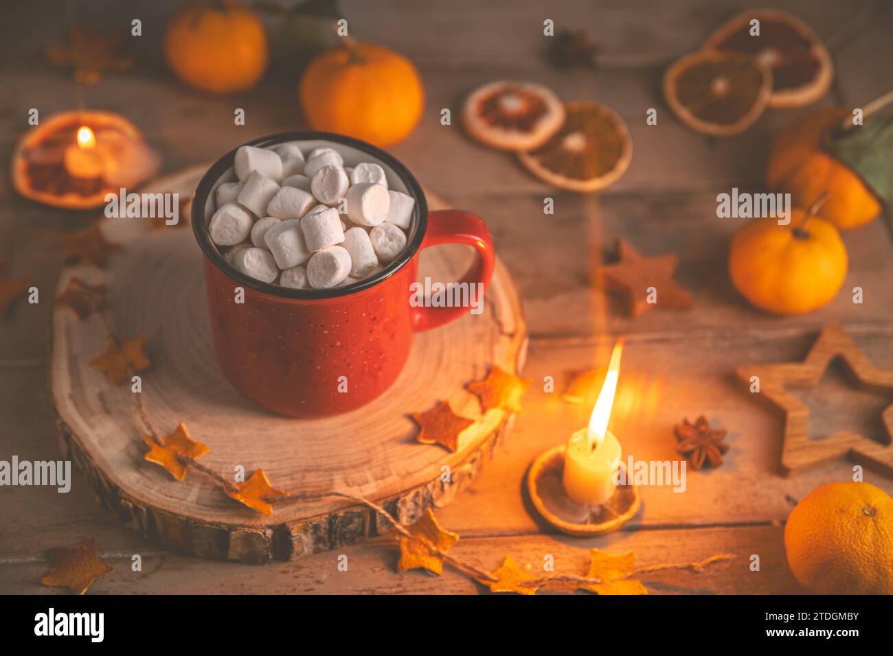 Niedliche, gemütliche Winterkomposition. Rote Tasse, Marshmallows, Weihnachtsbeleuchtung und Kerze. Silvester und weihnachten, Wärme, Komfort Stockfoto