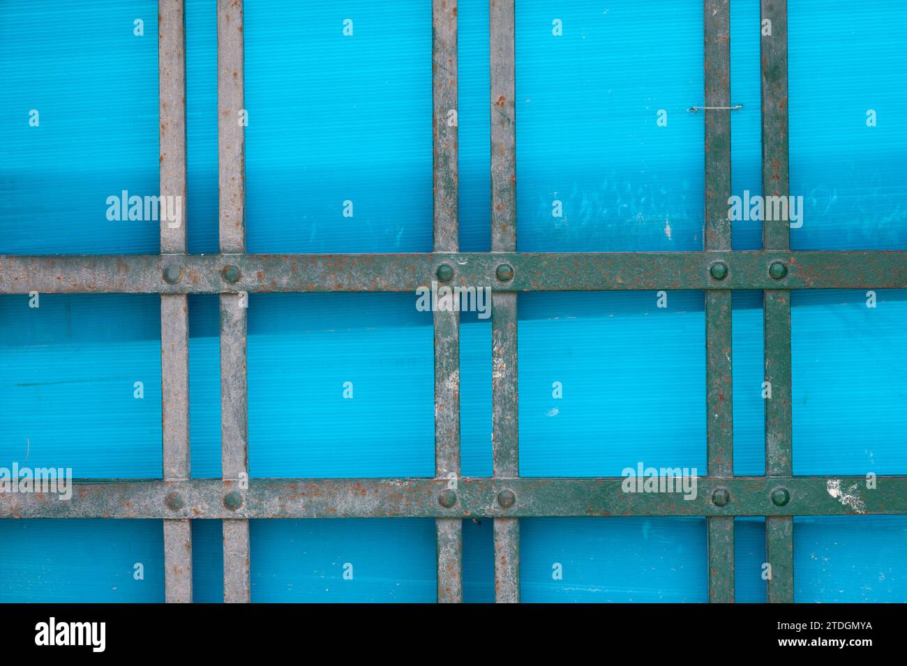Abstrakte Darstellung von Metallstäben, Linien und blauem Kunststoffmaterial, das eine Tür bedeckt. Stockfoto