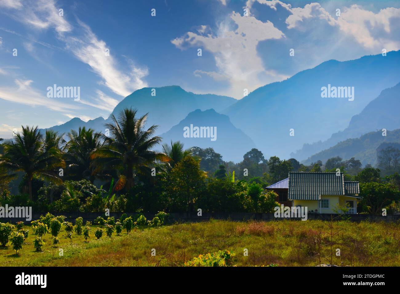 Ein Haus und der Garten mit Ernte, schönen Bergen und Himmel voller Wolken, Palmen und anderen Bäumen Thailand Stockfoto