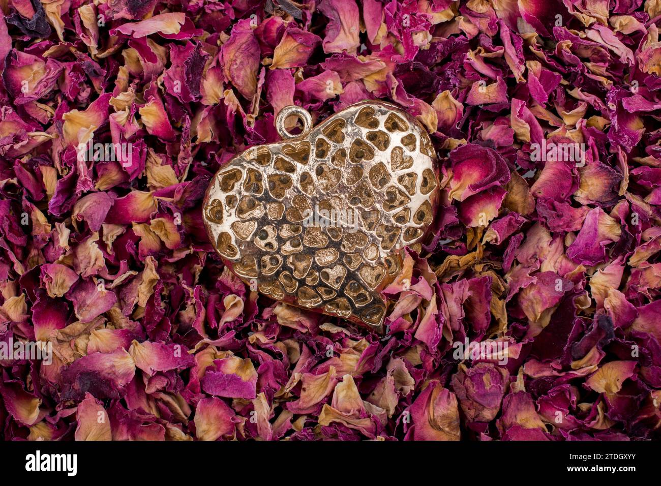 Goldene Farbe Herz auf trockenen Rosenblüten Hintergrund Stockfoto