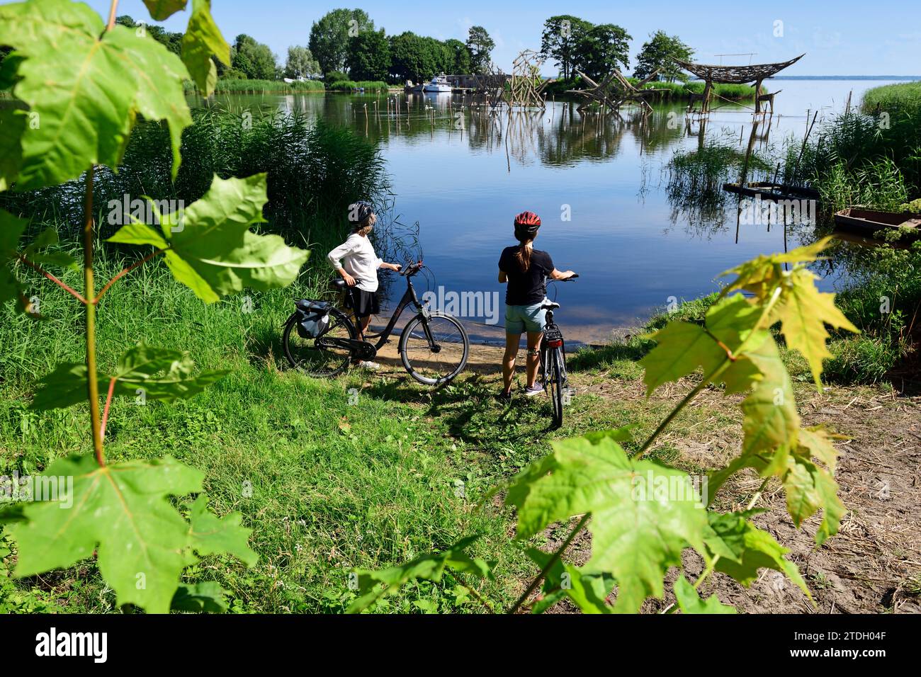 Radfahrer vor Holzskulpturen im alten Bernsteinhafen von Juodkrante, Litauen Stockfoto