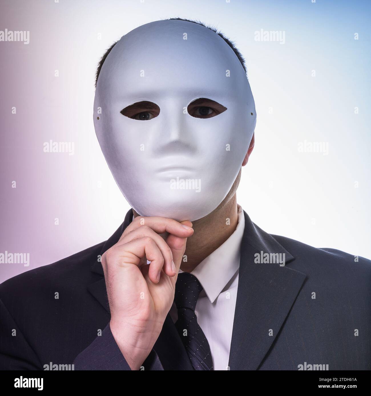 Ein Mann versteckt sein Gesicht mit einer Maske, ein Konzept zum Thema Spionage und Identitätsgeheimnisse Stockfoto