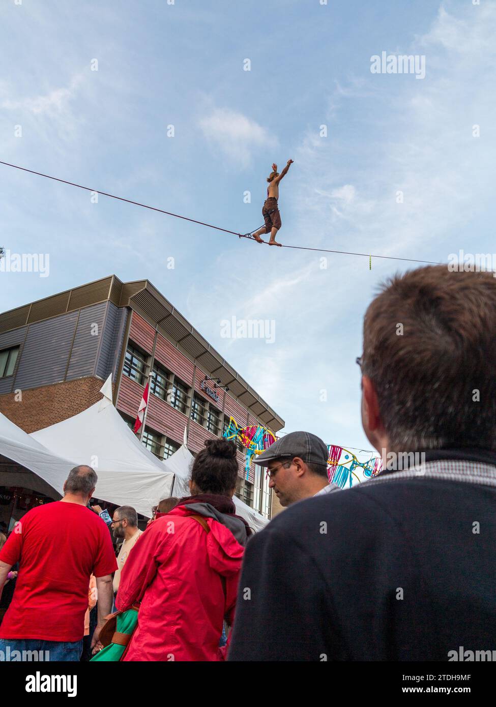 Ein Mann beobachtet während des Musikfestivals am Ende der Welt einen Balancer über einer vergänglichen Straße in Gaspé. Gaspé, Quebec, Kanada Stockfoto