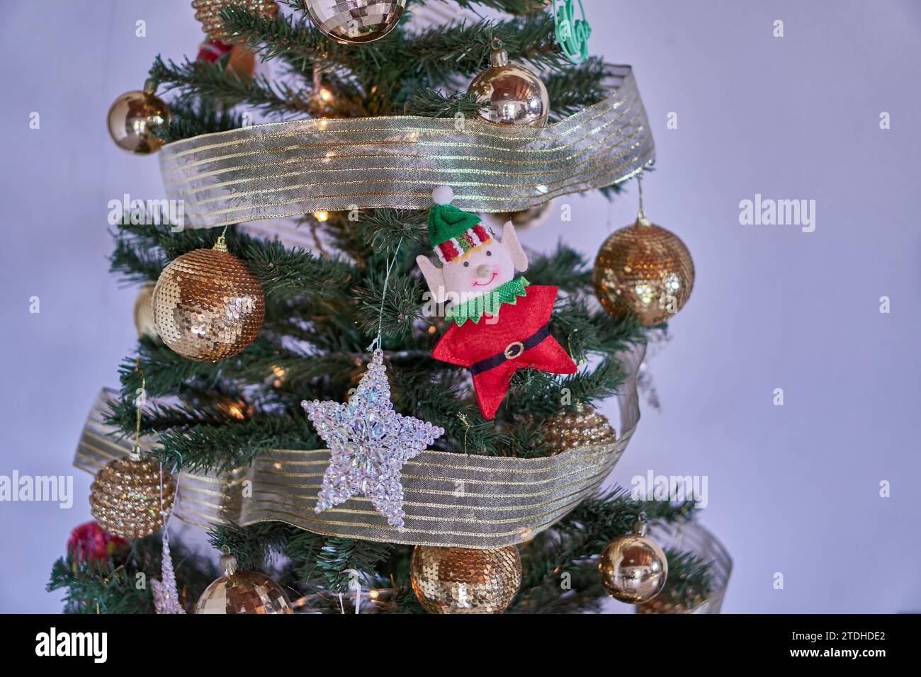 Weihnachtsbaumschmuck, goldene glitzernde Kugeln, ein glänzender Stern und Elfe, die in einem weihnachtsbaum auf weißem Hintergrund hängen. Horizontaler und Kopierbereich Stockfoto