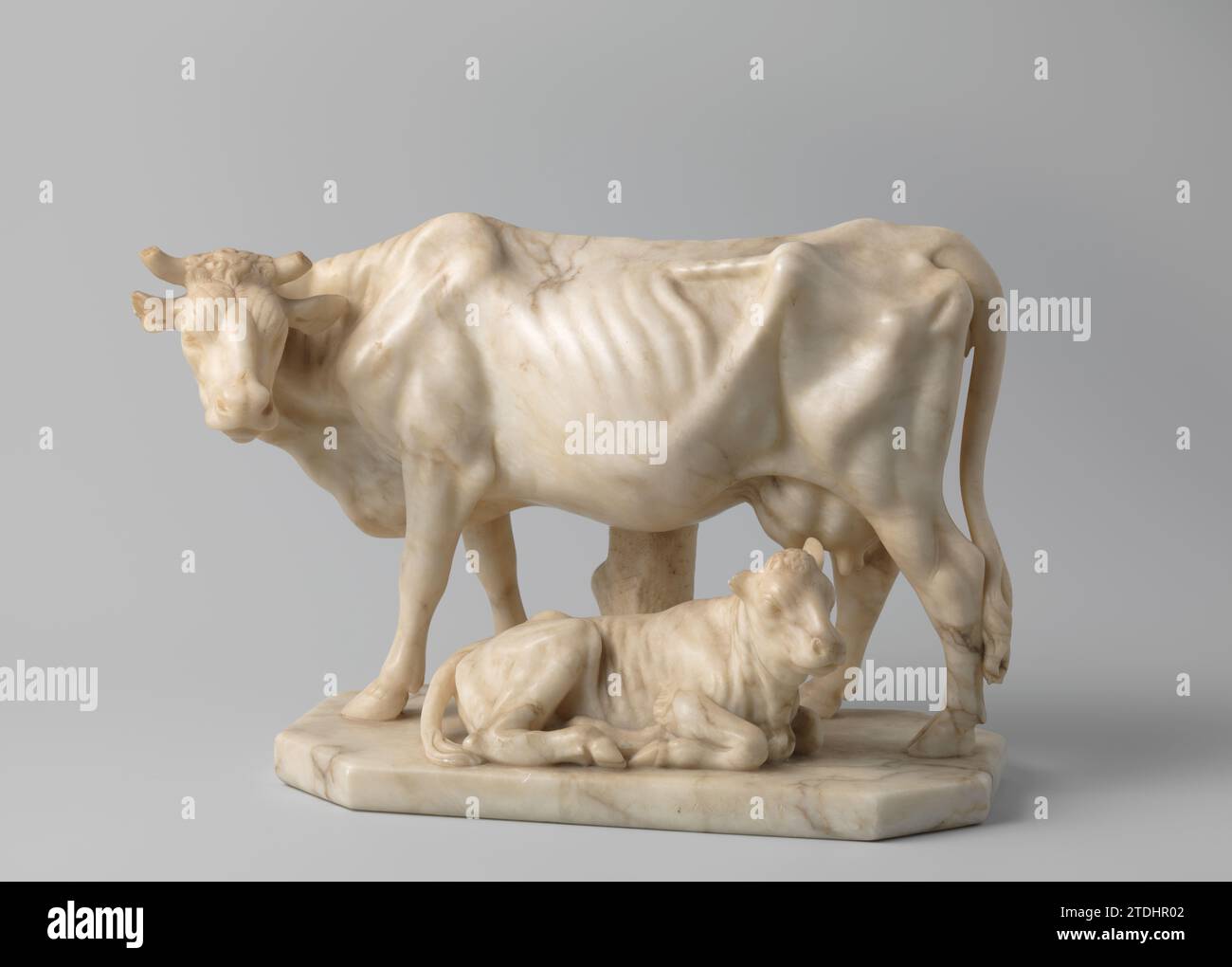 Skulpturengruppe Kuh und Kälber , 1800 - 1850 Skulpturengruppe Kuh und Kälber, naturalistische Skulptur in gelb-weißem Alabaster mit braun-grauer Ader. Die stehende Kuh zeigt nach links mit dem Kopf zur Seite. Da für ein Kalb, das nach rechts mit dem Kopf schräg nach vorne liegt. Hinten ein Baumstumpf als Stütze auf dem rechteckigen Sockel mit abgeschrägten Ecken. Hoorns-Kuh und rechtes Ohr-Kalb zerbrochen. Niederlande (möglicherweise) Alabaster (Mineral) Skulpturengruppe aus Kuh und Kalb, naturalistische Skulptur aus gelb-weißem Alabaster mit braun-grauer Ader. Die stehende Kuh zeigt nach links mit ihren Köpfen Stockfoto