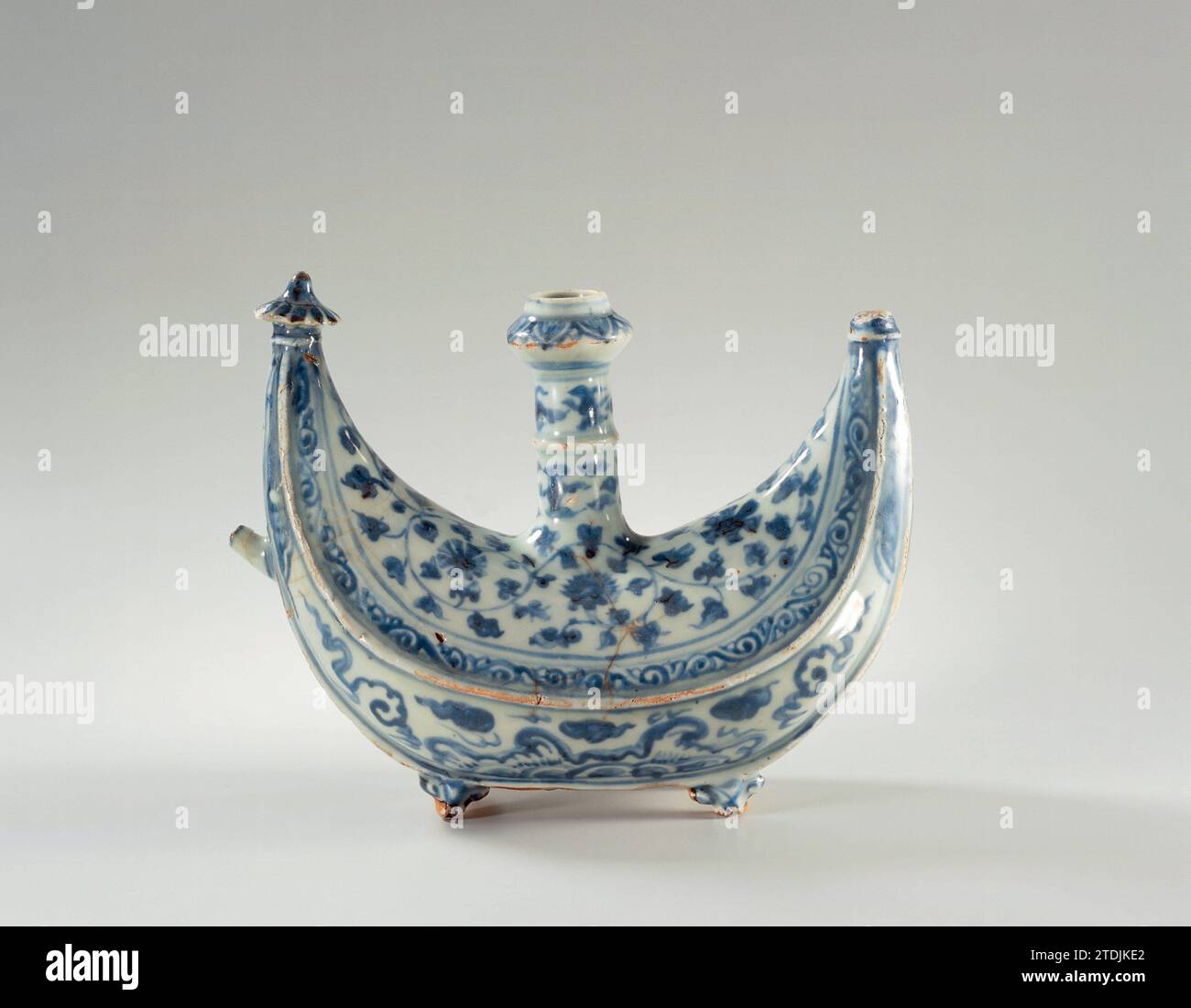 Ewer, anonym, ca. 1475 - ca. 1524 Kendi van Porzellan in Form eines Halbmondes auf vier kurzen Füßen, in der Mitte ein langer Hals mit Verdickung und ein kleiner Auslauf auf einer Seite, in Unterlazblau bemalt. Der untere Teil mit wirbelnden Wellen, Flammen und Wolken. Der obere Teil mit durchgehenden Blumenreben und einem Band mit Locken. Die Verdickung im Nacken mit stilisierten Blumenmotiven. Die Punkte der Sichel sind mit einer Schirmkrone versehen, von der eine fehlt. Ming Porzellan in Blau und weiß. Porzellan. Glasur. Kobalt-(Mineral-)Malerei / Verglasung Kendi van Porzellan in Form Stockfoto