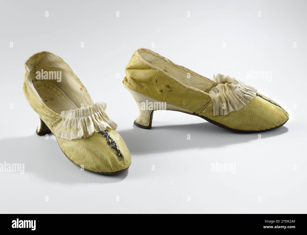 Damenschuh aus goldgelber genoppter Seide mit falten cremefarbenen Seitenstreifen und Silberliebhabern, anonym, ca. 1760 - ca. 1775 Damenschuhe aus goldgelber Genseide. Modell: Spitz zulaufende Nase, breiter Vorfuß, ein Deckblatt und zwei Seitenbleche. Die mit Ziegentheorie überzogene Ferse ist quadratisch geschnitten und verläuft unter der Gelbschicht bis zur Naht des Deckels. Die Ferse hat ein braunes Leder vom hinteren Schoß. Braune Rinderledersohle mit weißer Naht unter der Gelbsohle. Die Seitenlaken sind mit Ziegenleder eingezogen. Mit beigefarbenem Leinen bedeckt. Die Einlegesohle ist aus der Ziegentheorie. Dekoration: In der Mitte von Stockfoto