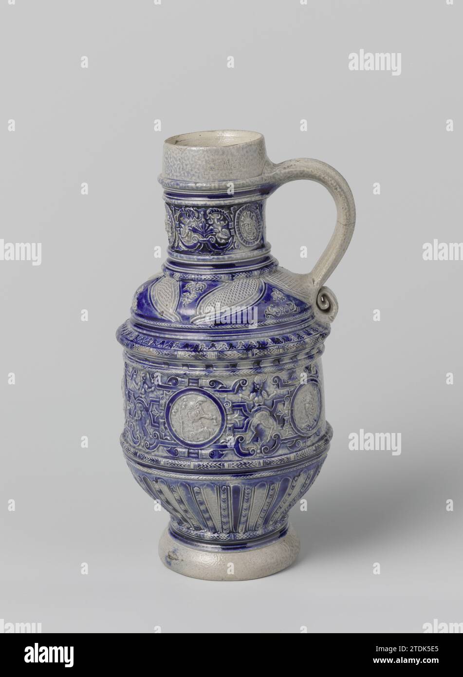 Krug mit Satyren, Porträts und Blumenrollen, anonym, ca. 1600 - ca. 1610 Krug Steinzeug auf hohem Fuß mit zylindrischem Korpus mit abgerundetem und unterem Hals. Die C-Form ist ebenfalls am Hals und an der Schulter befestigt. Profile an Hals, Körper und Fuß. Teilweise mit Kobaltblau bedeckt. Auf dem zylindrischen Teil ein durchgehendes Band im Relief von vier Satern zwischen gewellten Arbeiten, durchsetzt von fünf gedruckten und aufgedrückten Medaillons mit einem Porträt eines Mannes, einer Frau oder einer satie. Das mittlere Medaillon mit der Aufschrift 'im 90'. Der untere Teil des Abdomens mit Kanülen. Gestempelte Blume Stockfoto