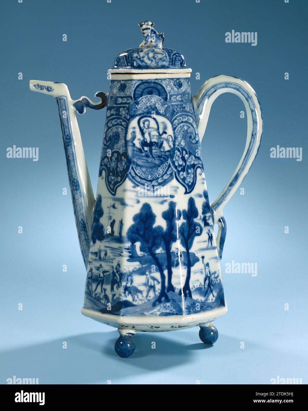 Achteckige Kaffeekanne mit Jagd- und mythologischen Szenen, anonym, ca. 1700 achteckige Kaffeekanne aus Porzellan auf drei kugelförmigen Füßen, ein konischer Körper mit geraden Wänden und C-förmigem Ohr, in unterliegendem Glasurblau gemalt. Der lange Auswurfkrümmer ist am Ende herausgebeugt und mit einem S-förmigen Element an der Oberseite mit dem Gehäuse verbunden. Die Wand ist in zwei Teile unterteilt. Die Unterseite mit einer kontinuierlichen Darstellung eines Jagdunternehmens in einer Landschaft. Die Oberseite besteht aus einem breiten, dekorativen Reifen mit Locken, Muschelmotiven, Servetwork, Blumenreben und zwei Kartuschen mit der mythologischen Darstellung von Stockfoto