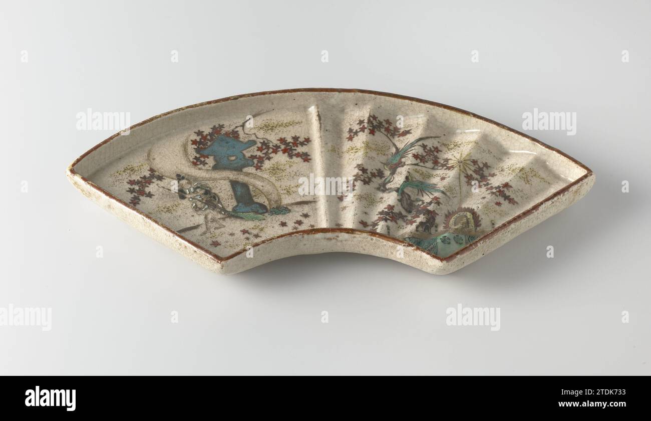 Fächerform mit Figur, blühenden Pflanzen und Vögeln, anonym, um 1700 - ca. 1799 Fächerförmiger Behälter aus Steinzeug, auf der Glasur in blau, rot, grün, gelb, braun bemalt, schwarz und Gold. Eine Hälfte des Bodens mit modellierten Rippen, die andere Hälfte ist glatt. Auf der rutschigen Hälfte einer Person mit Besenblättern, die nach einer Struktur und blühenden Pflanzen fegt (Ahorn?). Die andere Hälfte mit zwei Vögeln auf einer blühenden Pflanze in einer Struktur. Unter vertikalen, dekorativen Reifen. Drei alte Etiketten auf der Unterseite mit 'Owari. Shino-yaki / das 18. Jh. ist als Ornamental mit Golddust und Designs oder beschrieben Stockfoto