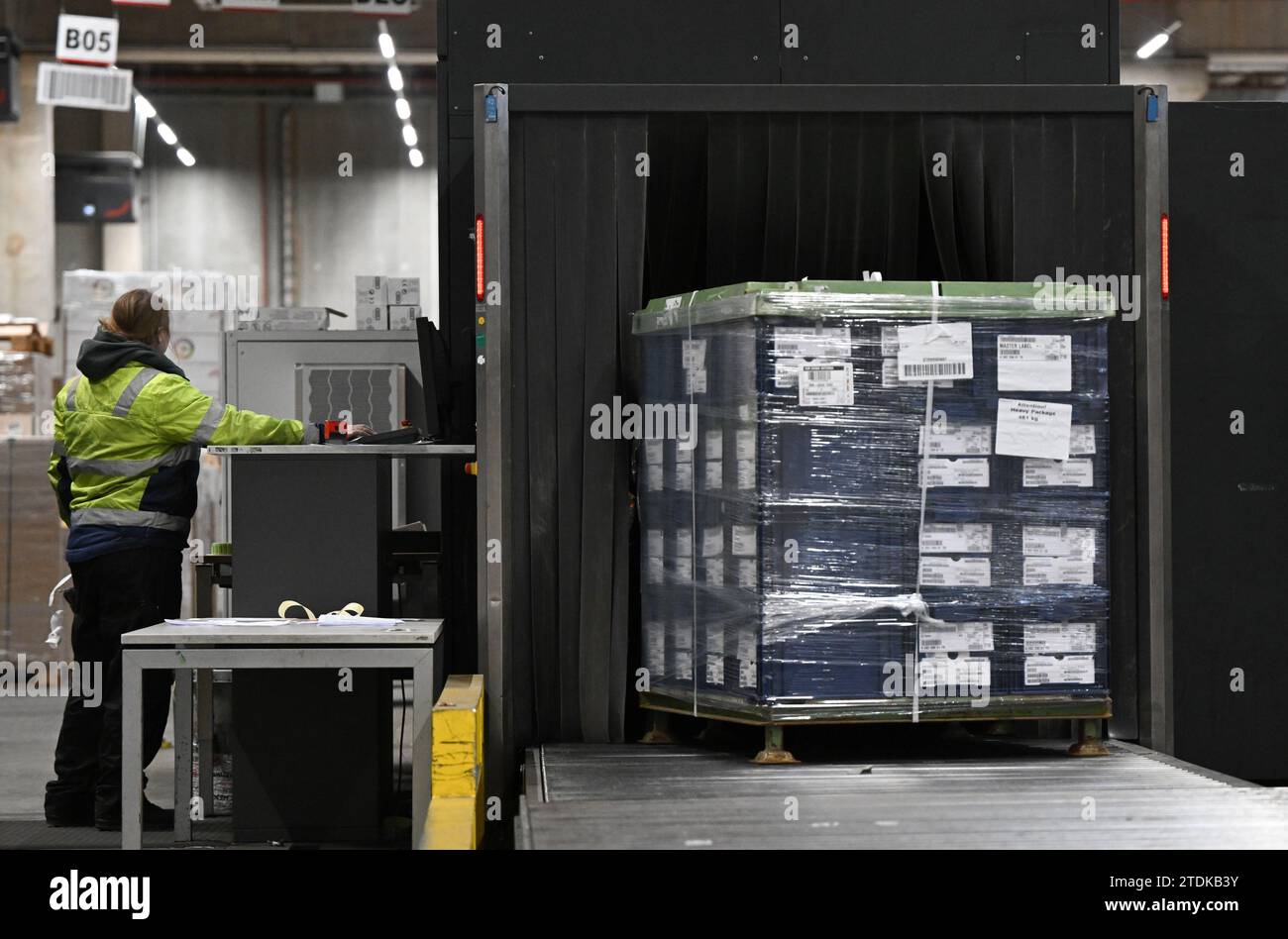 PRODUKTION - 07. Dezember 2023, Hessen, Frankfurt/Main: In der Luftfrachthalle von DB Schenker in der Cargo City Süd am Frankfurter Flughafen wird eine Palette in einen Röntgenscanner für die Paletten- und Frachtkontrolle eingelassen. Luftfracht ermöglicht den Transport einer Vielzahl von Objekten über Kontinente hinweg. Vor Weihnachten müssen sich die Dinge besonders schnell bewegen. (Zu dpa „wenn jeder Zentimeter zählt – Year-End-Spurt in der Luftfrachthalle“) Foto: Arne Dedert/dpa Stockfoto