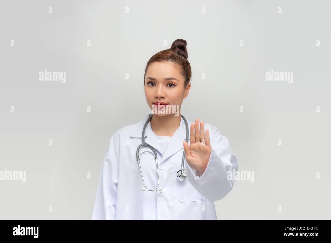 Schönheitsärztin im Mantel mit Stop-Hand-Geste Stockfoto