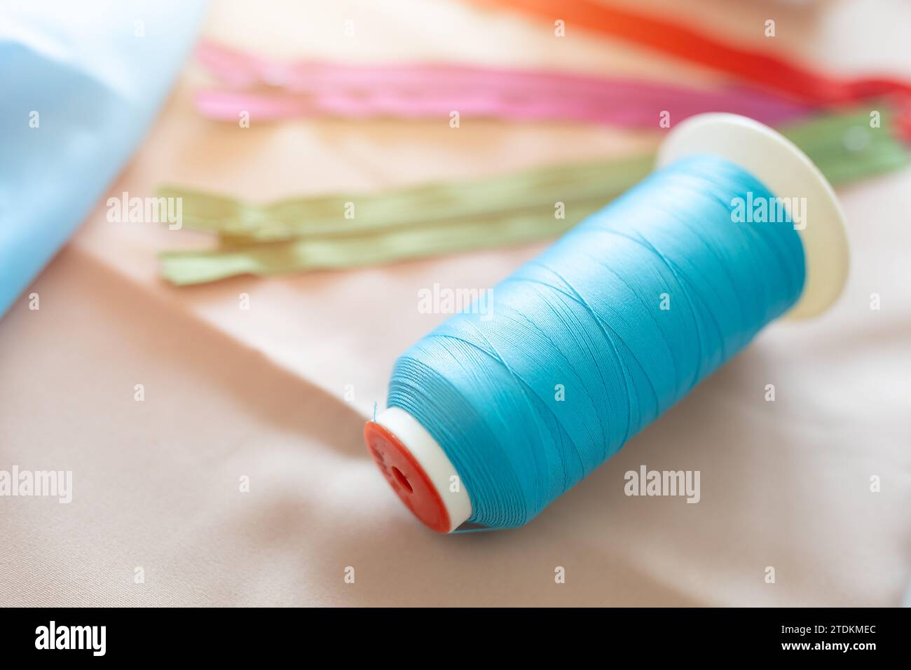 Fadenspulen zum Weben in automatischen Nähmaschinen aus maßgeschneidertem, farbenfrohem Industriekleidungsmaterial. Stockfoto