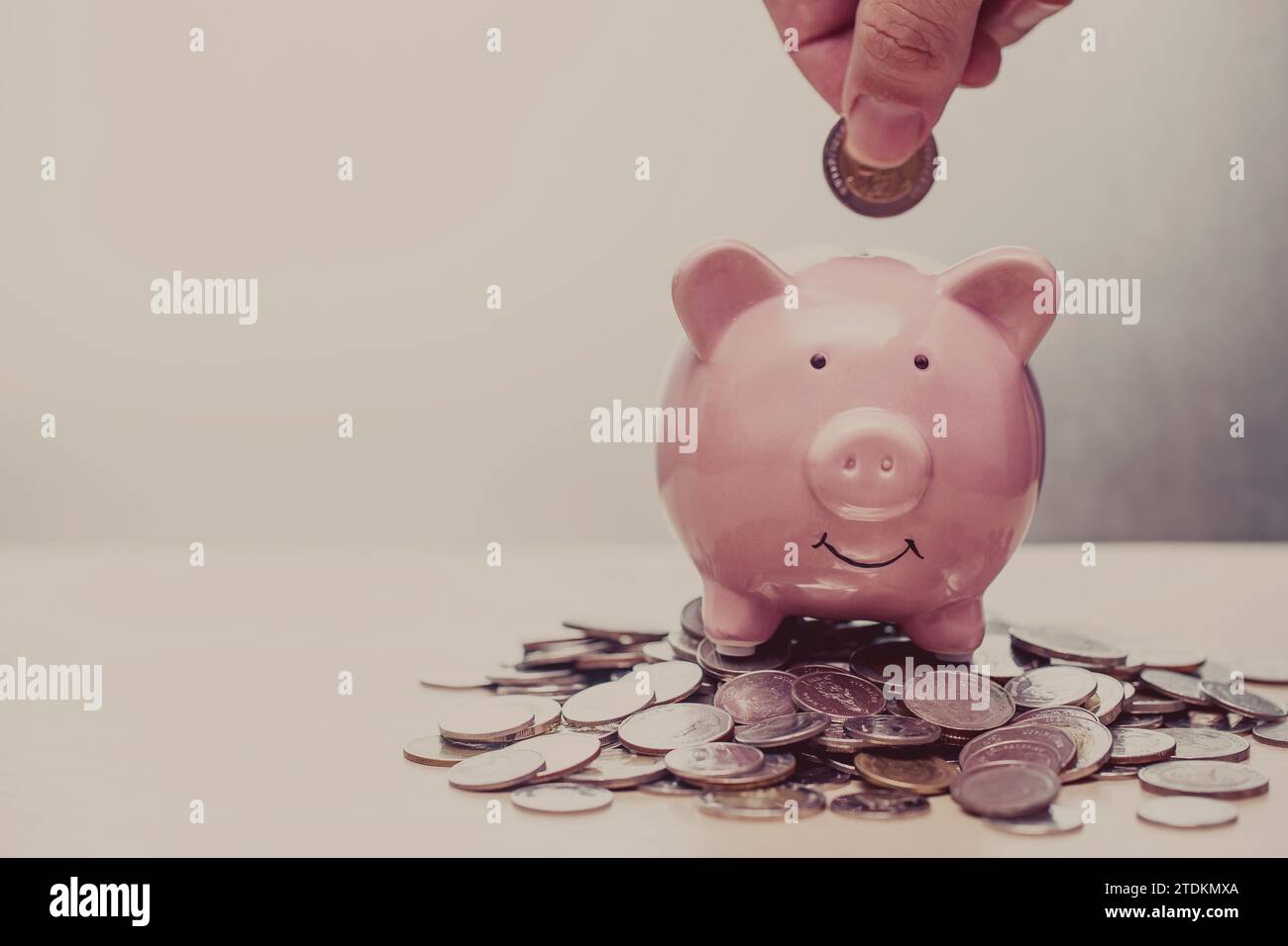 Hand Putting Coin to Piggy Bank Vintage Farbton für Business Banking Finance Konzept Werbungshintergrund. Stockfoto