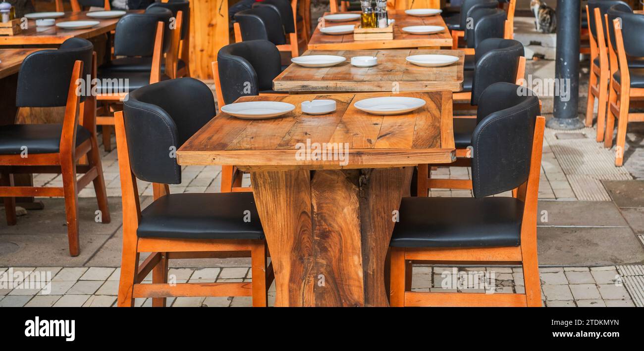 Restaurant im Freien. Altmodische Café-Terrasse. Holztisch. Café im Freien mit Holztischen. Natürliche Tische im Straßencafé an einem sonnigen Sommertag Stockfoto