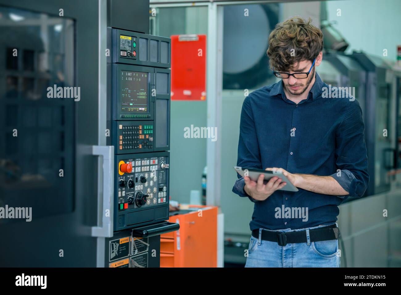 Junger Berufsingenieur männlicher arbeitender Programmierer automatischer CNC-Maschine in der Automatisierungs-Metallfabrik Stockfoto