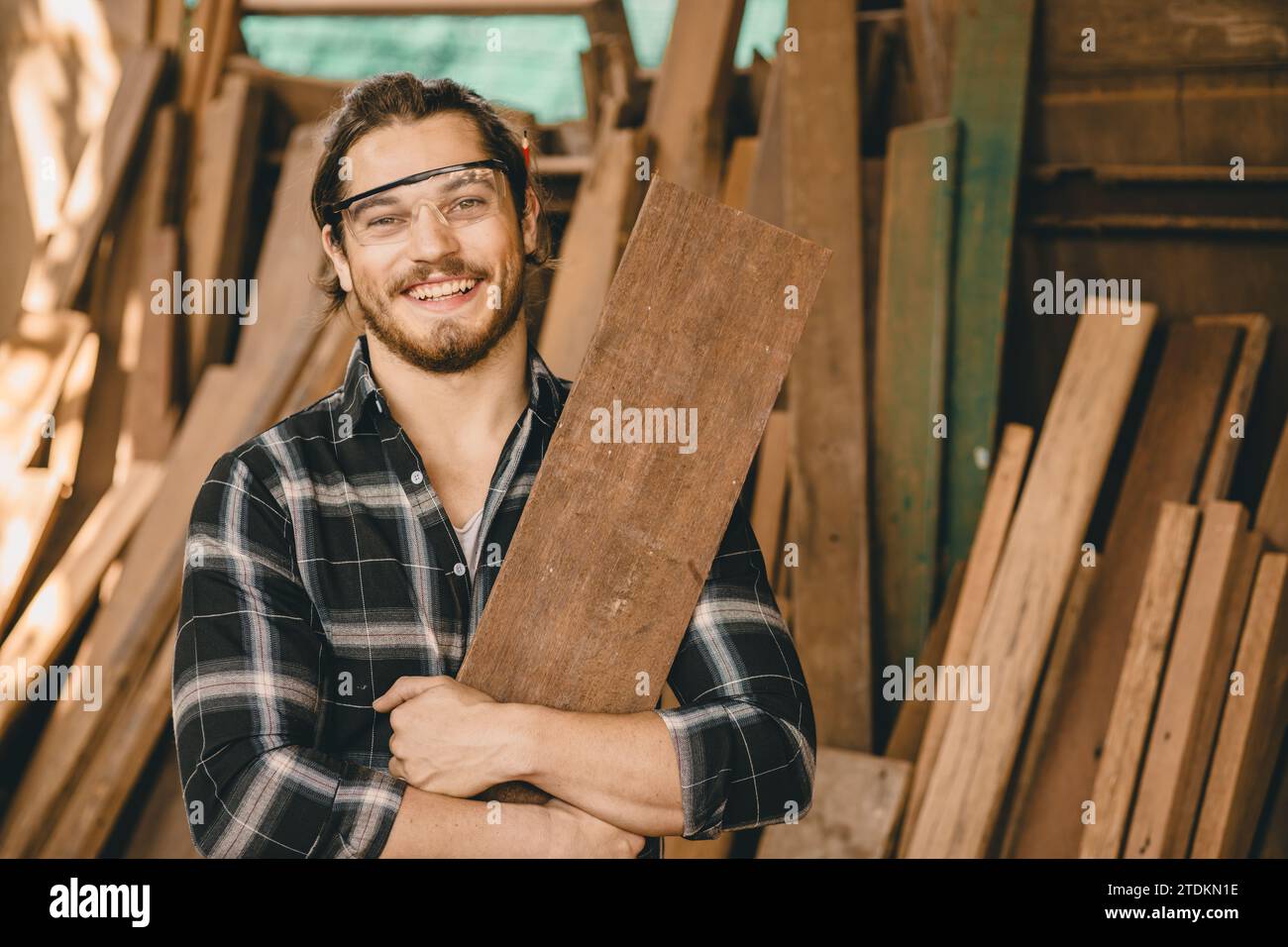 Portrait junger Zimmermann Handwerkerhandwerk Mann mit Holztafel glücklich lächelnd Stockfoto