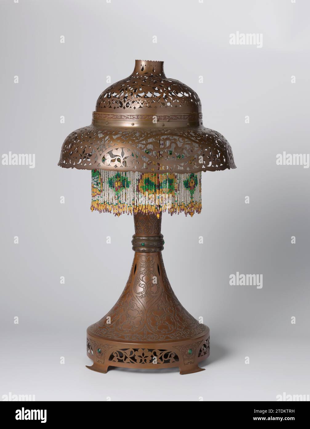 Dämmerung mit Ajour-Motiven, Theo Nieuwenhuis, in oder vor ca. 1914 die Lampe wurde aus vielen Teilen zusammengestellt. Diese sind mit geätzten und sorgfältigen oder ausgeschnittenen Rängen versehen oder nicht in der Motorhaube enthalten). Sie haben einen runden Fleckenring auf vier Füßen, ein Stamm, der sich vom Standring bis zur Mitte mit drei vertikalen Rippen verjüngt, zwei in -abgebildete Verbindungsstücke für die Teile der Haube oder eingearbeitete oder eingearbeitete Teile der Haube. Wo diese zusammenkommen, ist auch ein volant kleiner Glasperlen, in denen unter anderem Schmetterlinge und Libellen zu erkennen sind. T Stockfoto