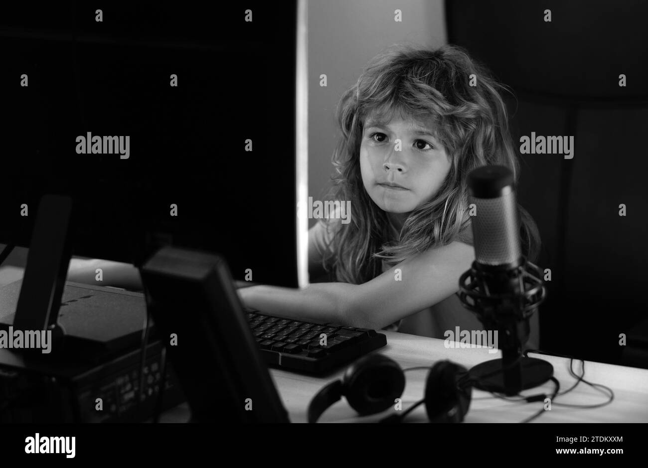 Das kleine Kind nutzt nachts einen Desktop-pc, das kleine Kind wird vom blauen Licht eines Computerbildschirms beleuchtet. Gamer spielen Desktop-Computerspiel. Gaming-Stream Stockfoto