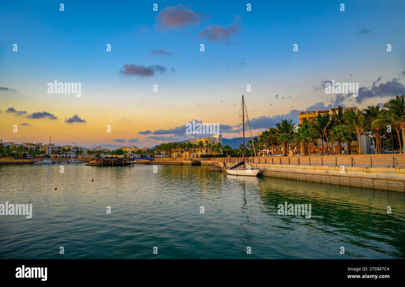 Sonnenuntergang am Hafen von Hawana Salalah mit Yachten, Resorts und Palmen im Oman Stockfoto