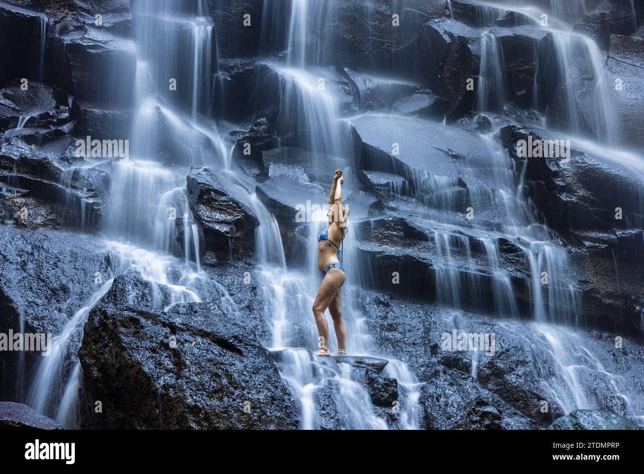 Eine junge Frau im Badeanzug am Kanto Lampo Wasserfall im üppigen tropischen Wald, Bali, Indonesien Stockfoto