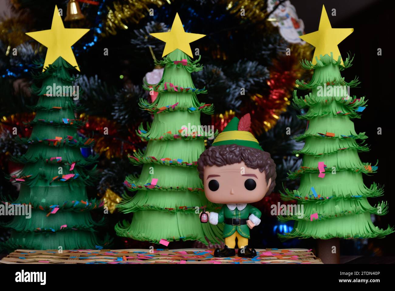 Funko Pop Actionfigur von Buddy aus dem Familienkomödie Elf. Weihnachtsbäume aus handgefertigtem Papier, Ornamente, Konfetti, Girlande, festliche Einrichtung. Stockfoto