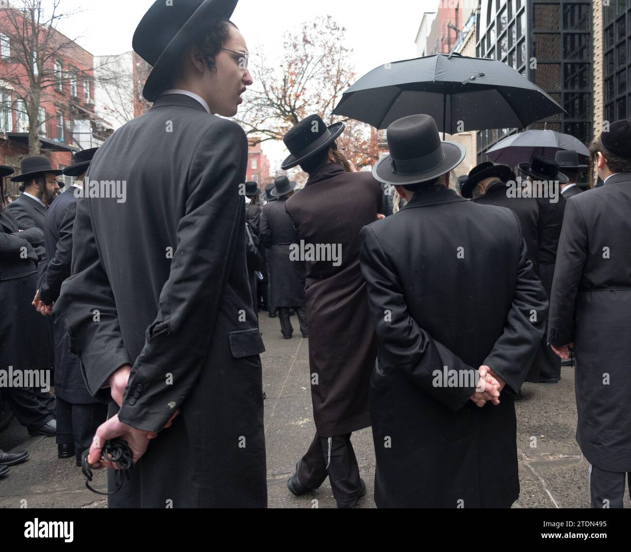 Orthodoxe jüdische Männer in schwarz gekleideter Kleidung nehmen an einer Beerdigung eines chassidischen Rabbiners Teil und hören sich eine Trauerfeier an. In Brooklyn, New York. Stockfoto