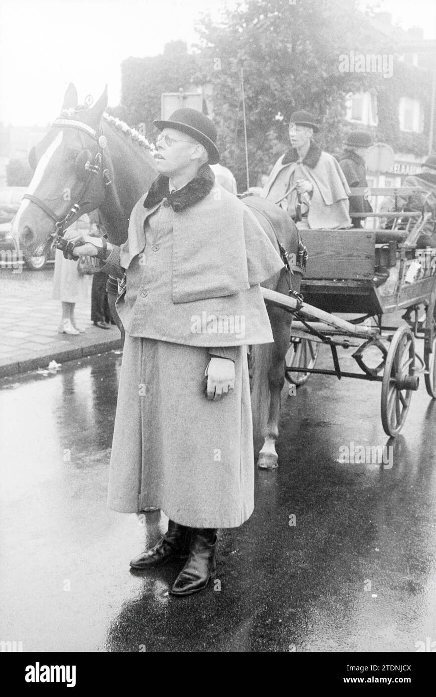 Prozession von Kutschen mit Pferden und Menschen in traditioneller Kleidung im Regen, Whizgle News aus der Vergangenheit, zugeschnitten auf die Zukunft. Erkunden Sie historische Geschichten, das Image der niederländischen Agentur aus einer modernen Perspektive, die die Lücke zwischen den Ereignissen von gestern und den Erkenntnissen von morgen überbrückt. Eine zeitlose Reise, die die Geschichten prägt, die unsere Zukunft prägen Stockfoto