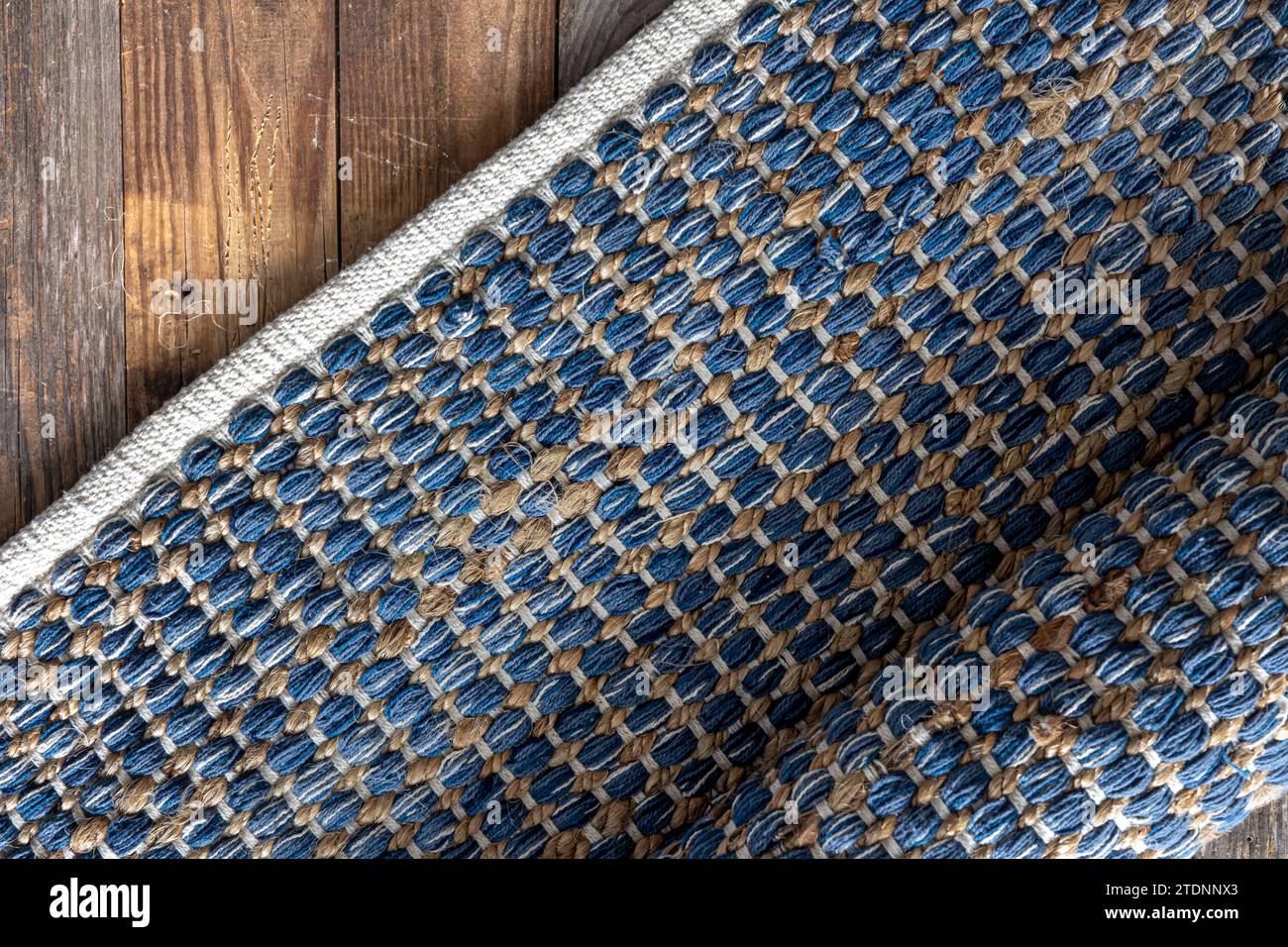 Handgewebter Teppich mit geometrischem Denim-Bereich auf Holzboden. Stockfoto