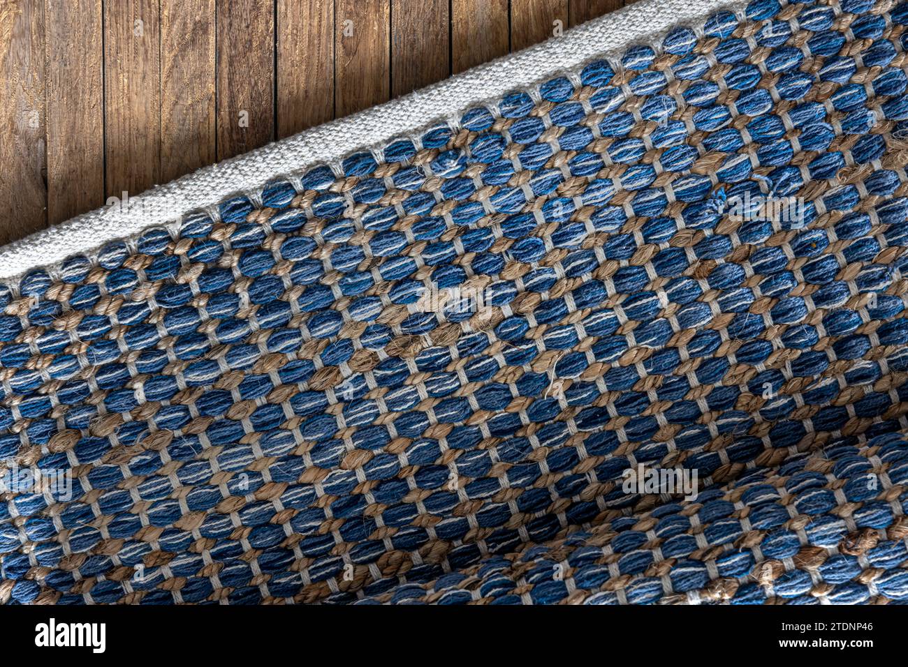 Handgewebter Teppich mit geometrischem Denim-Bereich auf Holzboden. Stockfoto