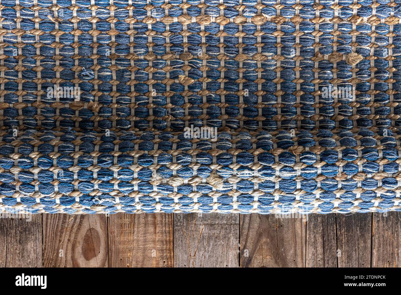Handgewebter Teppich mit geometrischem Denim-Bereich auf Holzboden. Stockfoto