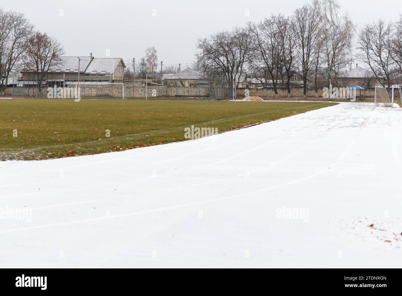 Leeres Stadion, Laufband, gepflastert, mit Markierungen für Läufer und Fußballfeld. Im Winter bei schneebedecktem Wetter Stockfoto