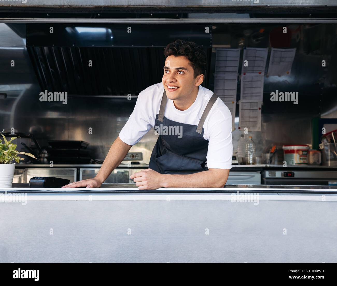 Porträt eines Imbisswagenbesitzers. Junger Mann, der als Koch in einem Imbisswagen arbeitet. Stockfoto
