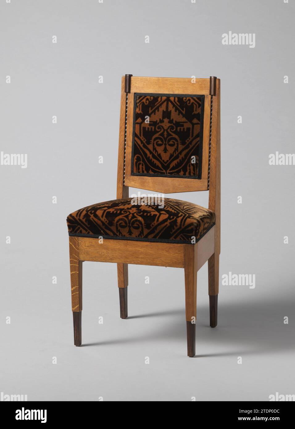 Stuhl bedeckt mit hellbraunem Trijp, Anonym, 1920 - ca. 1930 Stuhl aus Eiche und coromandel Holz auf vier Beinen. Die Beine sind unten verjüngt, der untere Teil besteht aus Coromandelhout. Die Hinterbeine werden in der erweiterten Rückenform fortgesetzt und verjüngen sich nach oben. Zwischen den vier Beinen gibt es breite Sitzregeln. An der Vorderseite, entlang der Backstyles, befindet sich eine Robbell-Liste, die von einem rechteckigen Block aus coromandel-Holz gekrönt wird. Die hintere Abdeckung befindet sich zwischen zwei seitlichen Ausführungen, einer unteren und einer oberen Schwelle. Der Schweller läuft unten in Dreiecksform aus. Sowohl die Rückseite als auch die s Stockfoto