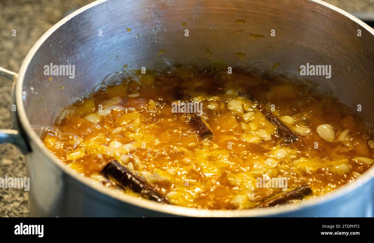 Hausgemachte Kürbismarmelade mit Mandeln und Zimtrollen, die gekocht und in einer Pfanne zubereitet werden Stockfoto